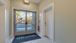 L’entrée d’un hôtel, avec une porte en verre, un extincteur et un paillasson portant l’inscription « Cityside ».