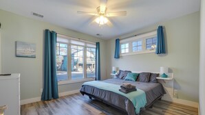 Une chambre à coucher avec un lit, un ventilateur de plafond, une fenêtre et une table de chevet.