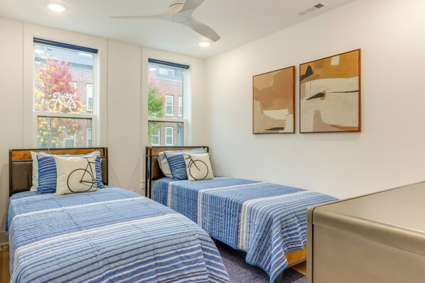 A hotel room with two beds, a ceiling fan, large windows, and abstract wall art. - Near Downtown: Luxury Townhome in Bentonville! (Bentonville)
