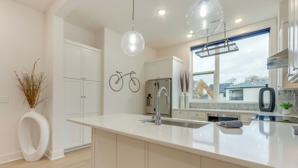 A modern kitchen with white cabinetry, a large island, stainless steel appliances, and pendant lighting. - Near Downtown: Luxury Townhome in Bentonville! (Bentonville)