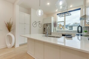 A modern kitchen with white cabinetry, a large island, stainless steel appliances, and pendant lighting. - Near Downtown: Luxury Townhome in Bentonville! (Bentonville)