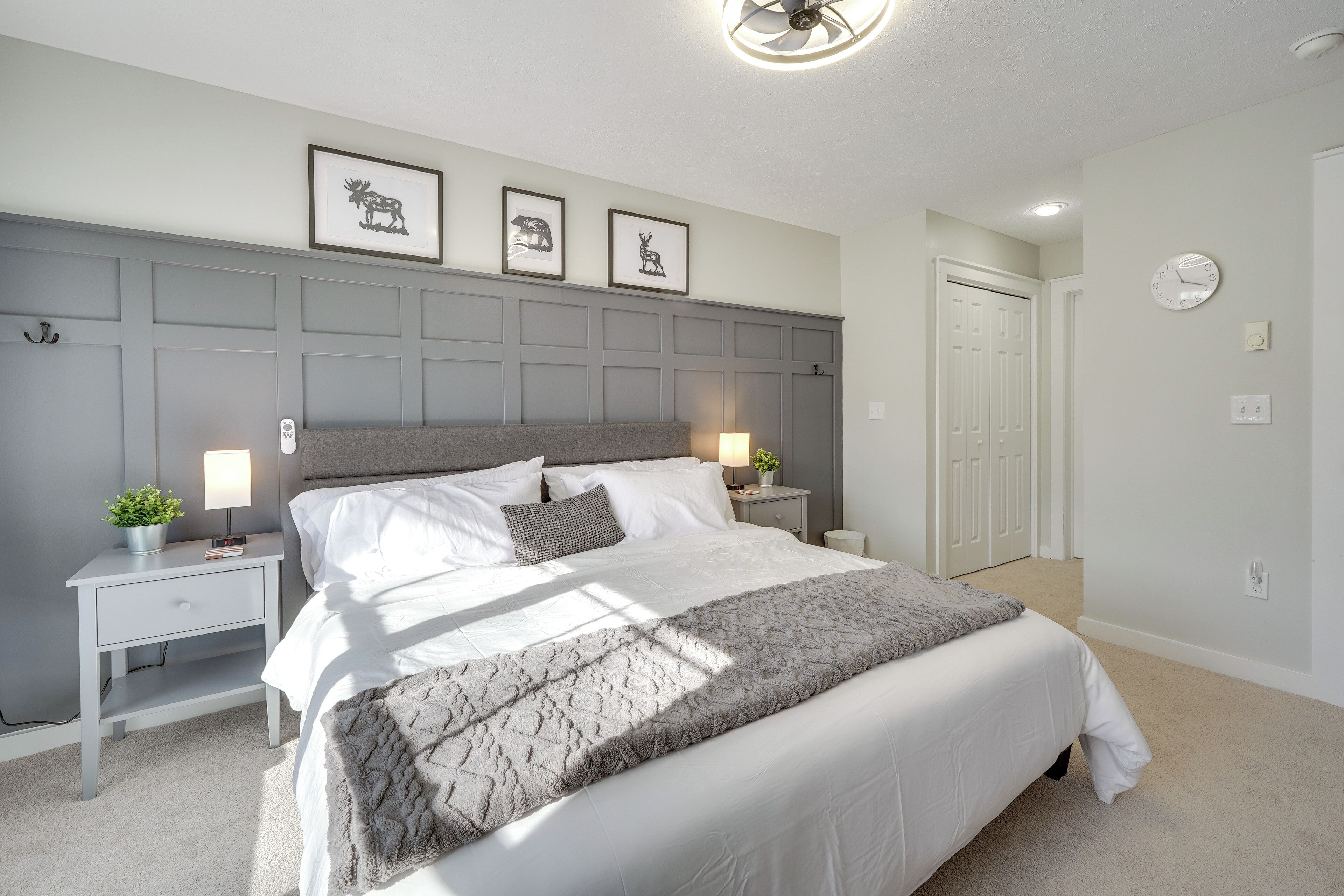 A bedroom with a large bed, bedside tables, a headboard, and framed pictures on the wall.