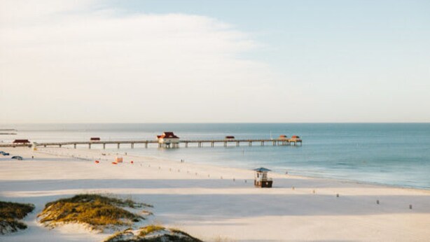 A beach with a pier extending into the water, a lifeguard tower, and a sandy shore. - Beach 2 Blocks Away Heated Pool Waterview Suite (Clearwater Beach)