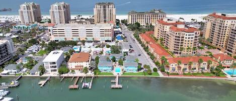 Un paisaje urbano costero con hoteles altos, un puerto deportivo con barcos y una playa al fondo.