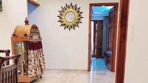A spacious room with a marble floor, a wooden cabinet, and a decorative mirror on the wall.