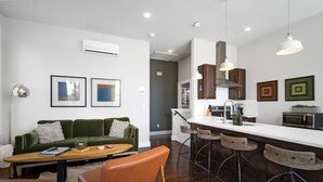 A modern kitchen with a bar area, a green sofa, and a coffee table. - Rackensack Inn Summar (Bentonville)