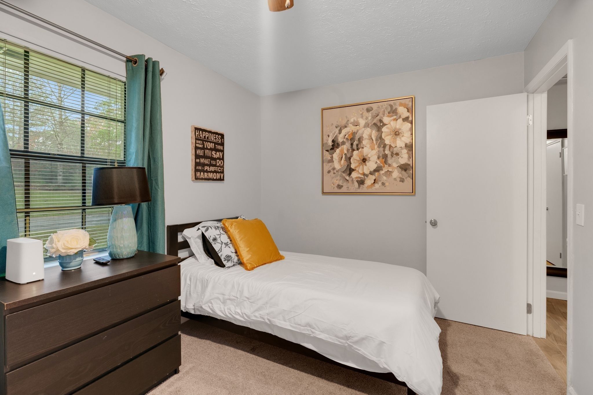 Quarto com cama, penteadeira, luminária e obra de arte na parede.