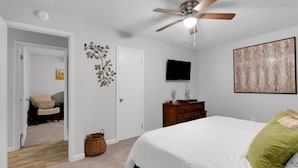 A bedroom with a bed, a ceiling fan, a TV, a dresser, and a painting on the wall. - Family-friendly 3br Oasis In Powder Springs 3 Bedroom Home (Powder Springs)