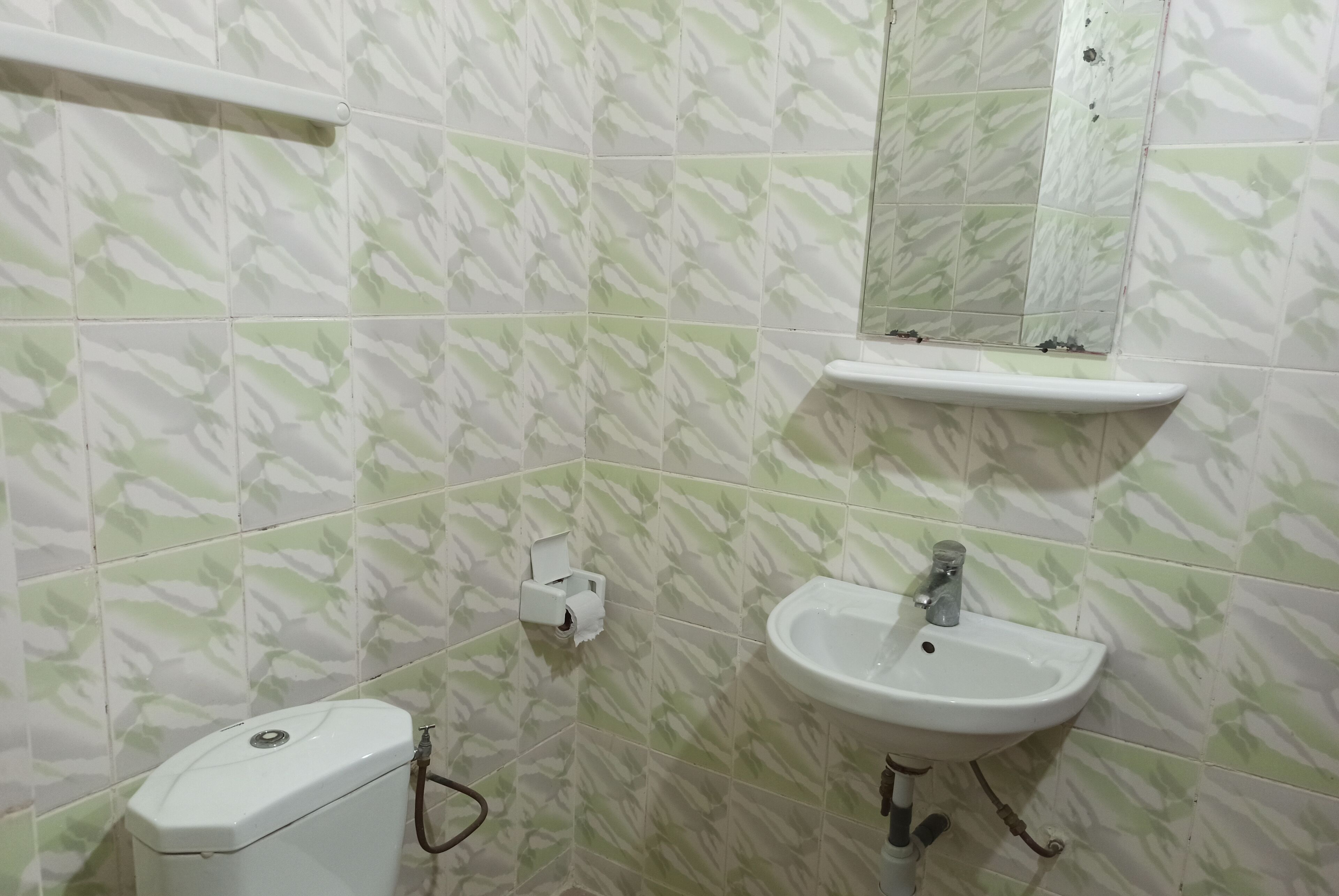 A bathroom with patterned tiles, a toilet, a sink, and a mirror.