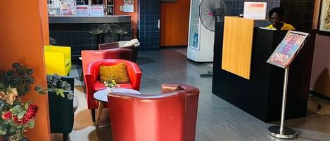 A reception area with a counter, a fan, and seating.