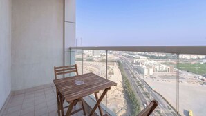 Ein Balkon mit Holztisch und -stühlen, mit Blick auf eine Stadtlandschaft aus Gebäuden und Straßen.