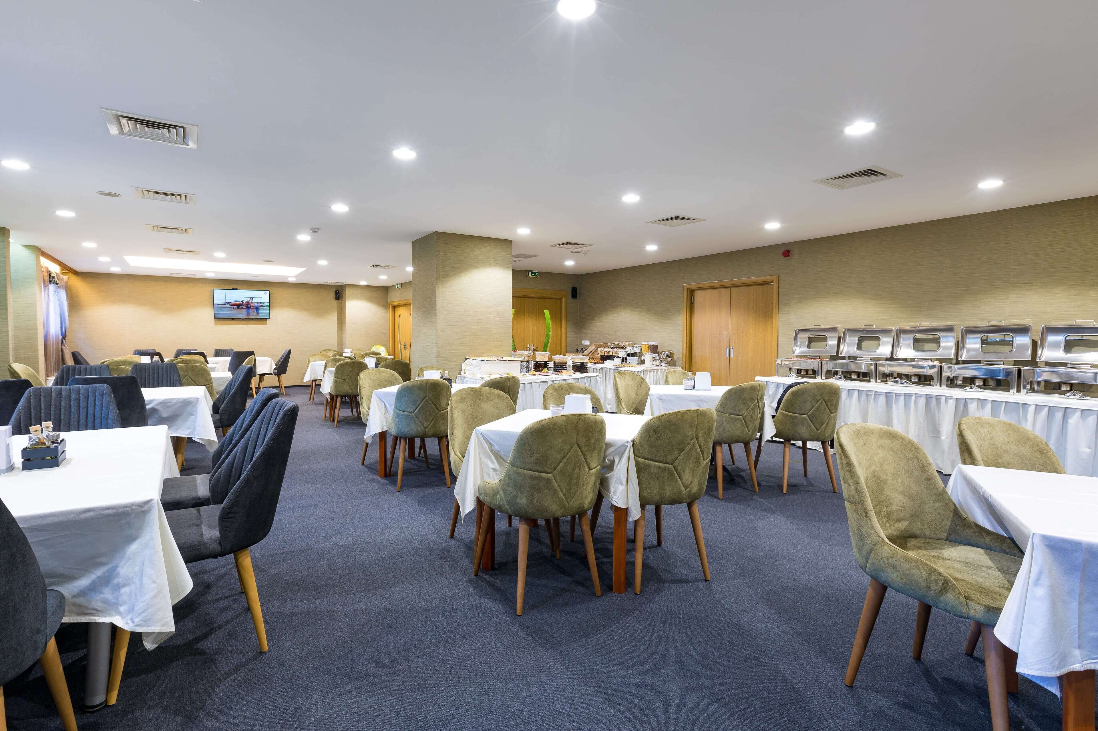 A conference room with multiple tables and chairs, a television screen, and a buffet area.