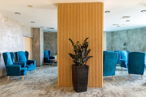 Guests can sit comfortably in the semi-circle of armchairs, surrounded by a contemporary design element and lush greenery.