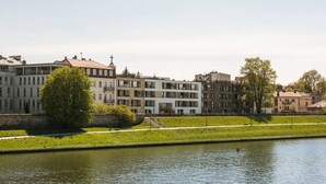 A river with buildings along the banks, a tree, and a grassy area.