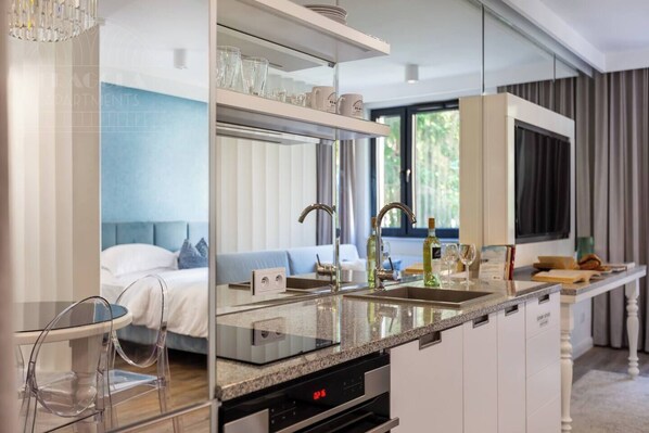 Habitación de hotel moderna con cocina, una mesa de comedor y una cama con vistas al exterior.