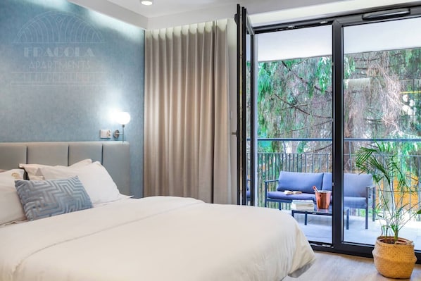 A bedroom with a bed, a nightstand, a lamp, a sliding glass door to an outdoor area with a chair and a table.