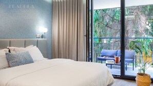 A bedroom with a bed, a nightstand, a lamp, a sliding glass door to an outdoor area with a chair and a table.