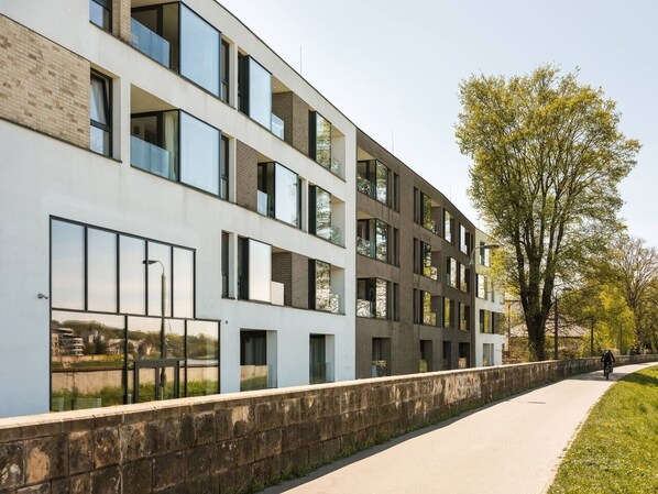Un edificio moderno con varios pisos, amplias ventanas y un paseo pavimentado.