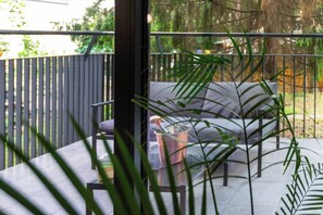 Un patio con un sofá, una mesa y un recipiente de vidrio.