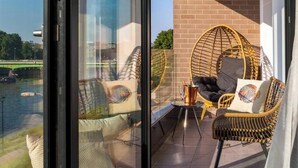 A balcony with wicker furniture, a view of a river, and a brick wall.