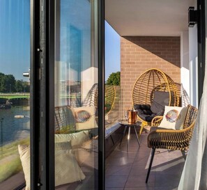 A balcony with wicker furniture, a view of a river, and a brick wall.