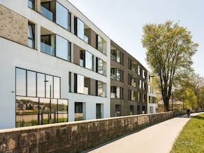 A modern building with multiple floors, large windows, and a paved walkway.