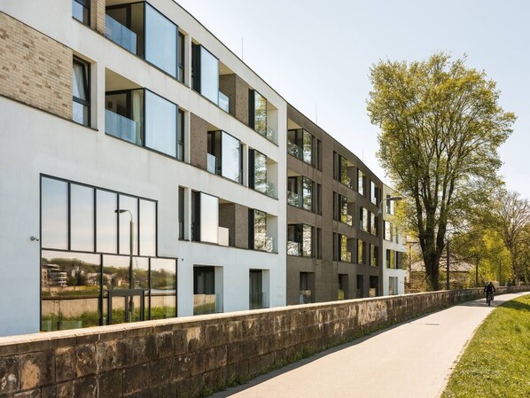 Un bâtiment moderne à plusieurs étages, doté de grandes fenêtres et d’un trottoir dallé.