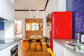 Una cocina moderna con un refrigerador rojo, un comedor con pared de ladrillo y un espejo grande.