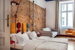 Une chambre avec un mur en briques, un lit, un canapé, une chaise et une fenêtre.