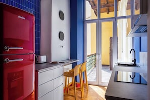 A modern kitchen with a red appliance, a white countertop, and a view of the outside.