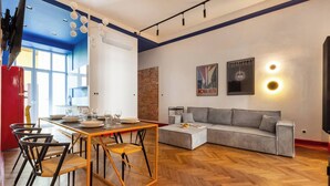 A modern living room with a dining area, a sofa, and a TV. - The Geometric 3-bedroom apartment (Kraków – Old Town)