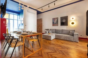 A modern living room with a dining area, a sofa, and a TV. - The Geometric 3-bedroom apartment (Kraków – Old Town)