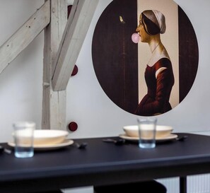 A table with a framed painting, a glass, and a plate.