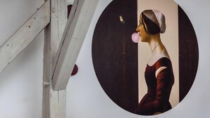 Una mesa de comedor con una obra de arte enmarcada, un vaso y un plato.