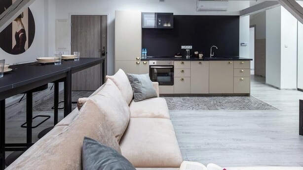 Una sala de estar moderna con sofá, una mesa de comedor y una zona de cocina con armarios y electrodomésticos.