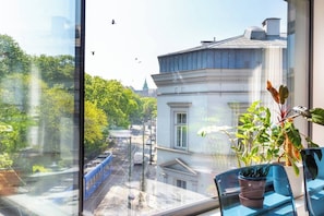 A view from a window with a building, trees, and a clear sky. - Apartment Modern Spacious (Kraków – Modern View of Planty Park)