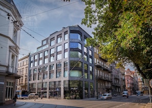 Um edifício moderno de vários andares, com grandes janelas, um restaurante no andar térreo e uma linha de eléctrico nas proximidades.