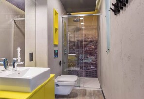 Un baño moderno con ducha envuelta en vidrio, un lavabo blanco y un inodoro.