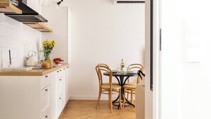 A modern kitchen with white cabinetry, a wooden countertop, and a dining area with a table and chairs. - Canvas House Apartament Oatmeal (Kraków)