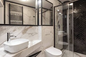 Une salle de bain avec un lavabo en marbre blanc, des toilettes et une douche fermée par une paroi de verre.