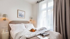 A neatly made bed with a quilted cover, a framed picture on the wall, and a bedside lamp. - Canvas House Apartament Oatmeal (Kraków)