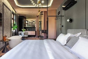 Una habitación de hotel moderna con una cama grande, un escritorio y una kitchenette.