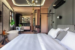 A modern hotel room with a large bed, a desk, and a kitchenette. - Canvas House Studio Rose & Tub (Kraków)