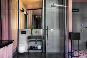 Un baño moderno con cabina de ducha de vidrio, tocador negro y retrete blanco.