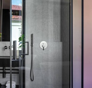 Un baño moderno con cabina de ducha de vidrio, un perchero visible y zona de lavabo.