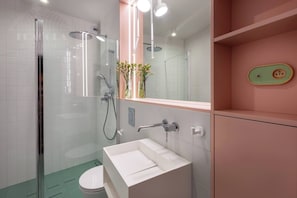 A modern bathroom with a glass-enclosed shower, a white sink, and a mirror above the sink.