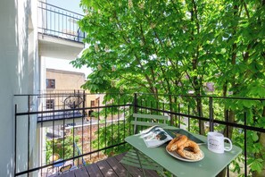 A balcony with a table, a chair, a newspaper, a plate with pretzels, and a mug. - Canvas House Apartament Pastel (Kraków)
