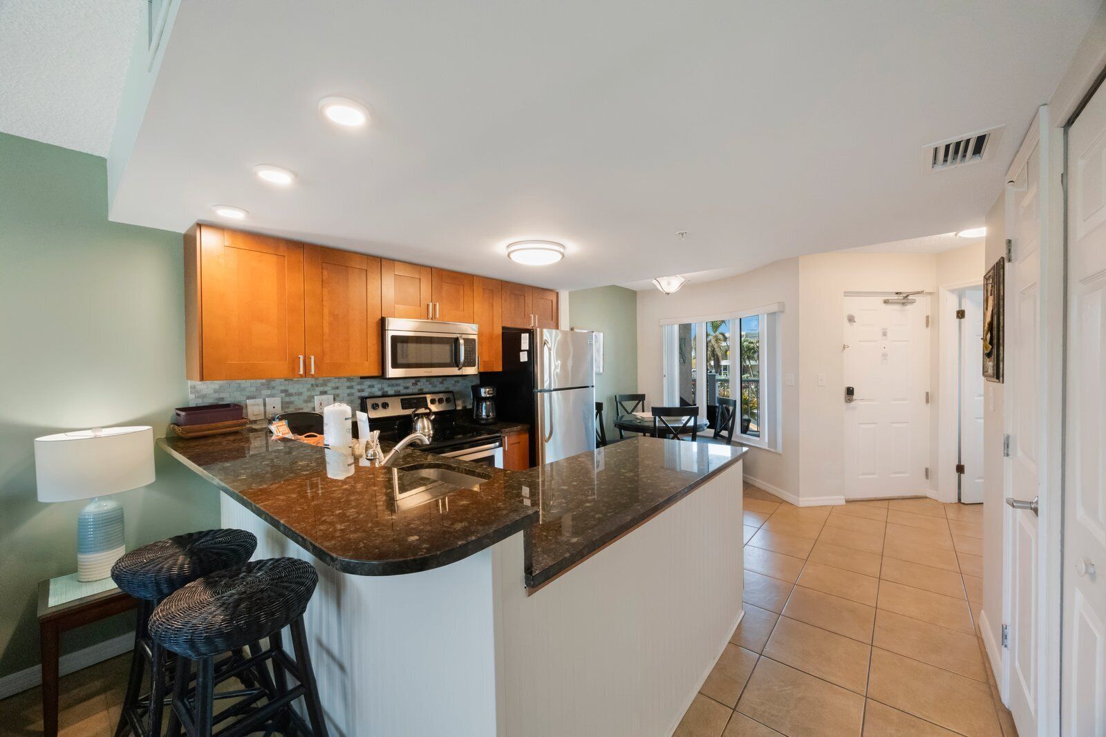 Una cocina moderna con armarios de madera, electrodomésticos de acero inoxidable y una isla grande con taburetes de bar.