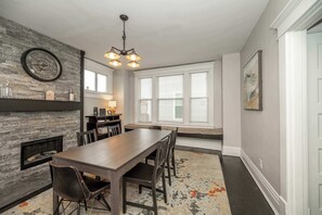 Cozy dining area with a long table, comfortable chairs, and a fireplace.