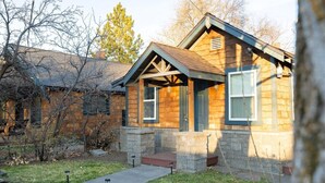 A two-story house with a stone facade, a front porch, and a visible chimney.